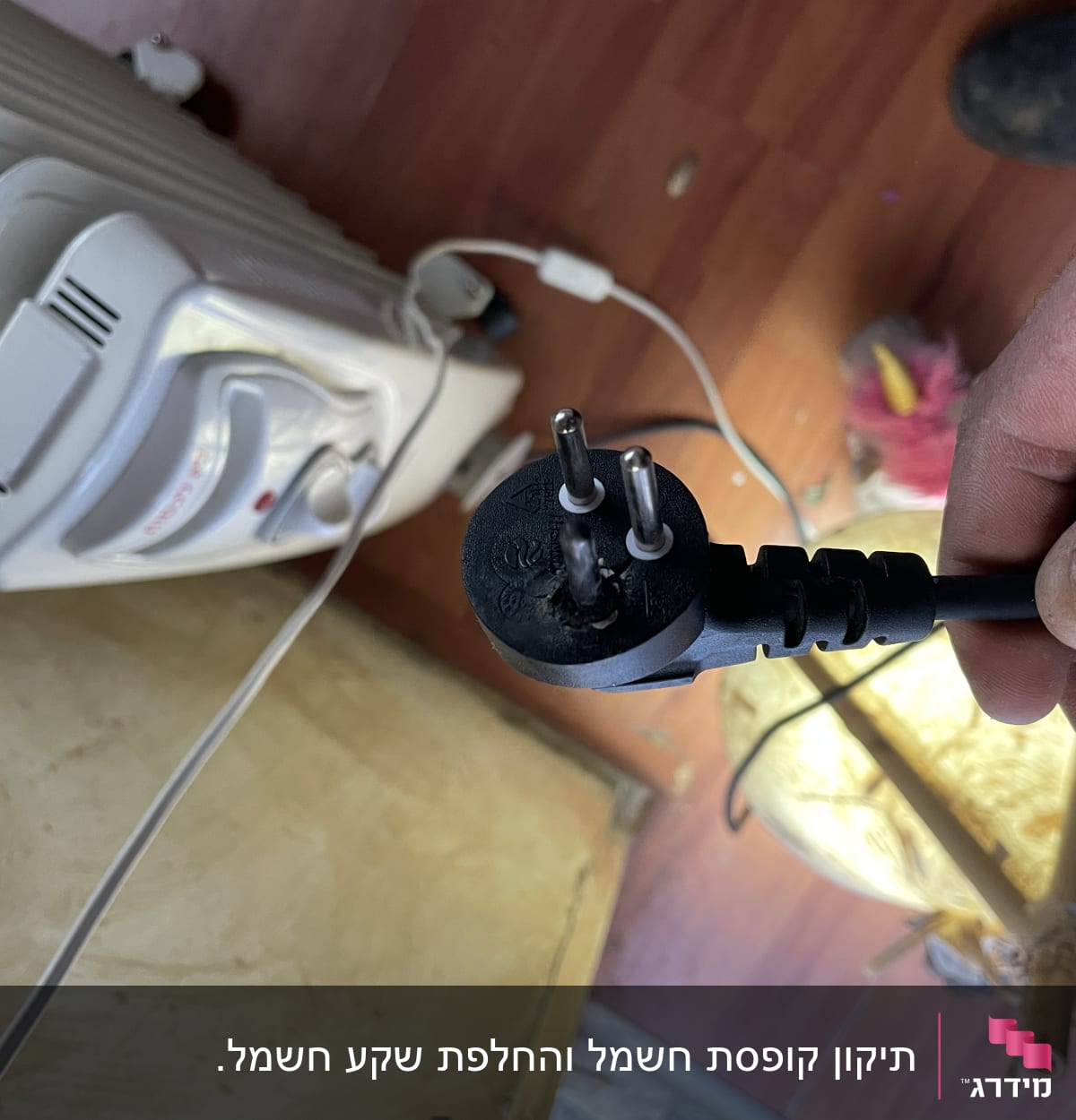 תקע חשמלי ביד מול תנור חימום חשמלי